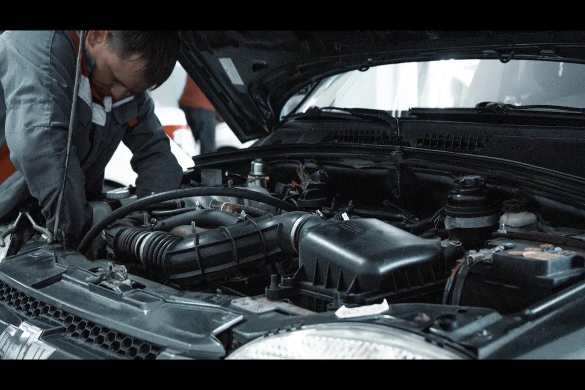 A technician leaning into an open engine bay